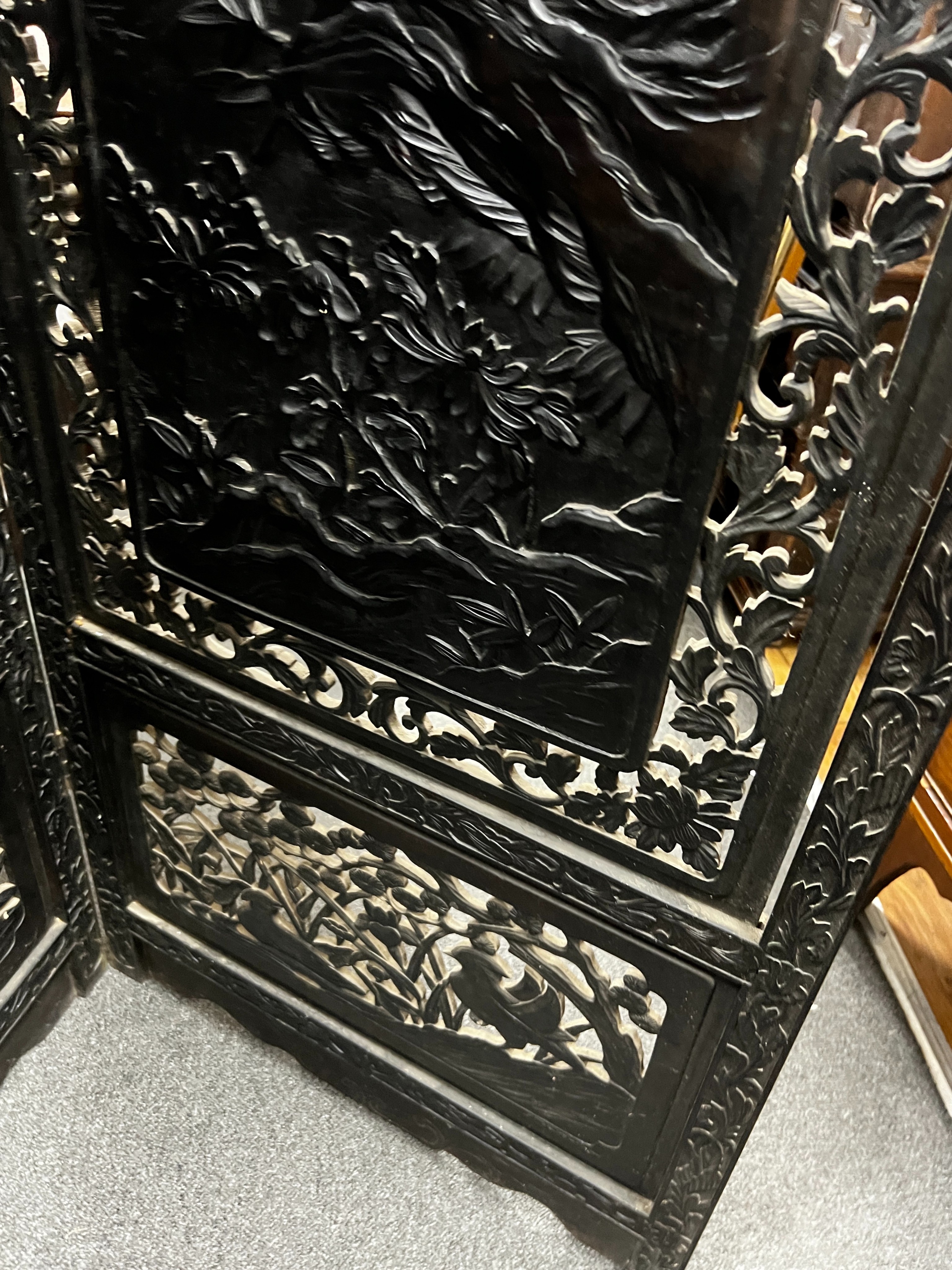 An early 20th century Japanese carved ebonised wood four fold dressing screen, width 56cm, height 173cm